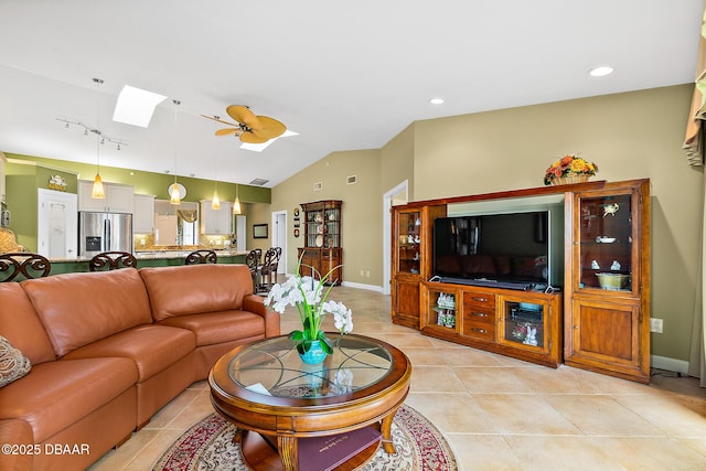 tiled living room with ceiling fan, lofted ceiling with skylight, and rail lighting