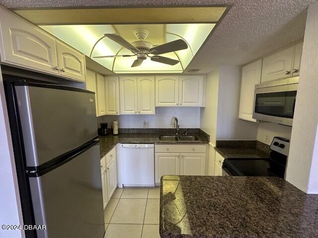 kitchen featuring stainless steel appliances, white cabinetry, light tile patterned floors, sink, and ceiling fan