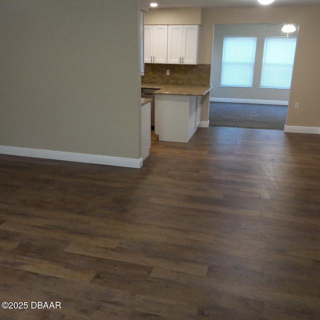 kitchen with open floor plan, white cabinets, dark wood-type flooring, baseboards, and tasteful backsplash