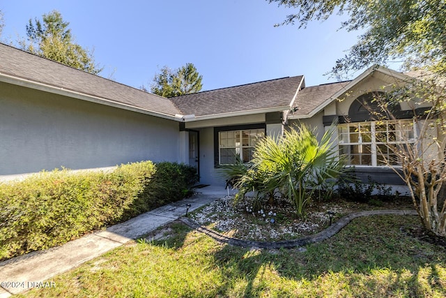 74 Fulton Pl, Palm Coast, FL 32137 - view of exterior entry featuring stucco siding and roof with shingles