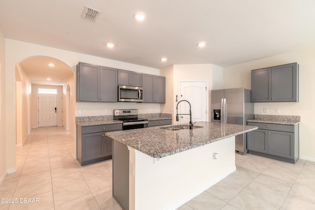 kitchen featuring gray cabinets, appliances with stainless steel finishes, a kitchen island with sink, and sink