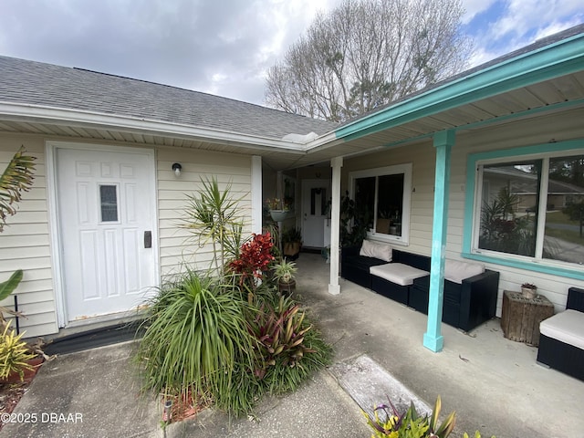 view of exterior entry featuring a porch and roof with shingles