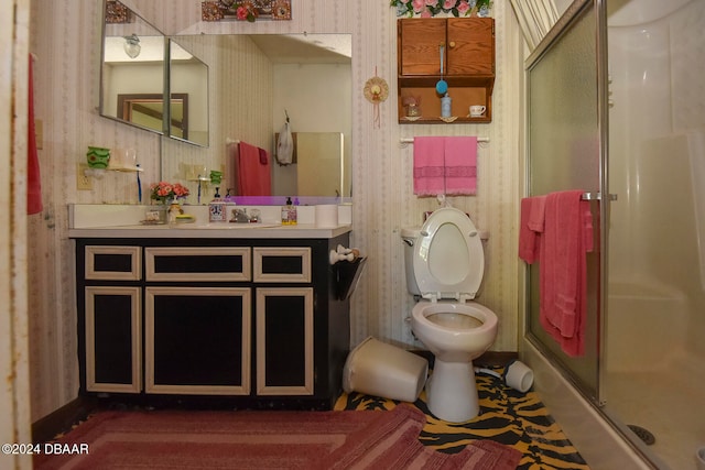 bathroom featuring vanity, toilet, and a shower with door