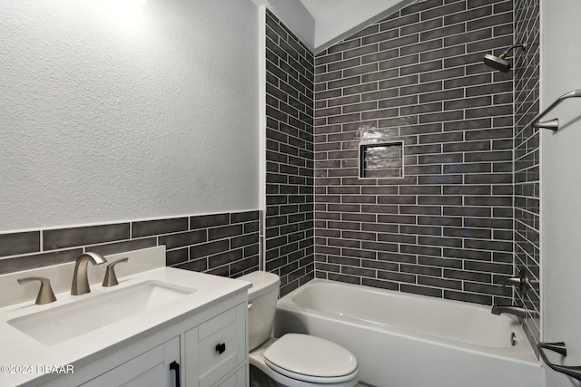 full bath featuring a textured wall, toilet, bathtub / shower combination, vanity, and tile walls