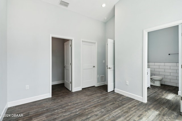 unfurnished bedroom featuring connected bathroom, visible vents, and dark wood finished floors