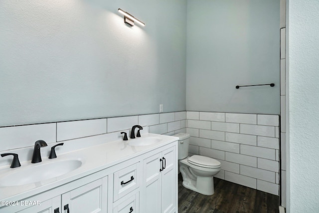 bathroom with wood finished floors, a sink, toilet, and tile walls