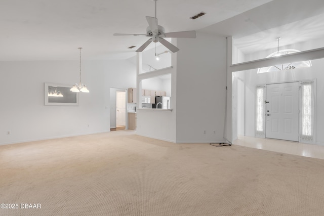 unfurnished living room featuring high vaulted ceiling, carpet flooring, and ceiling fan with notable chandelier