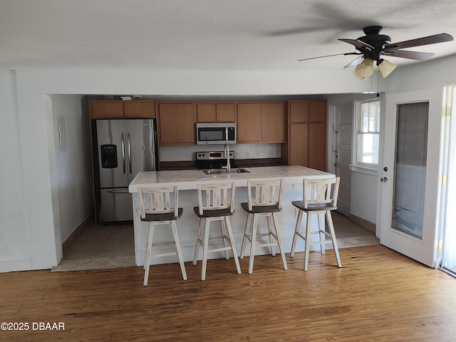 kitchen with light countertops, light wood-style floors, appliances with stainless steel finishes, and a sink