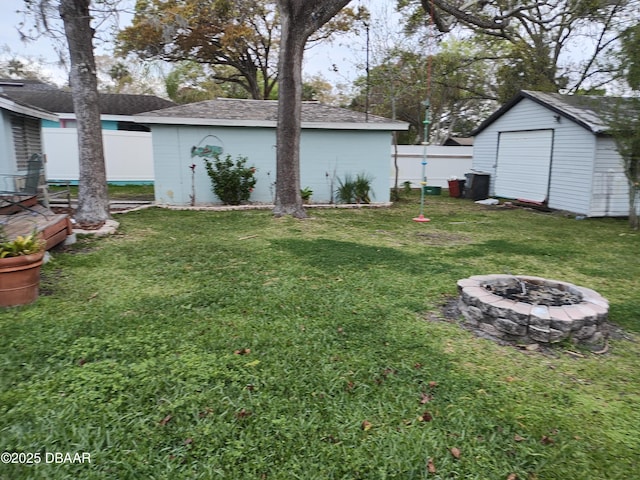 view of yard with an outbuilding, a shed, a wooden deck, a fenced backyard, and a fire pit