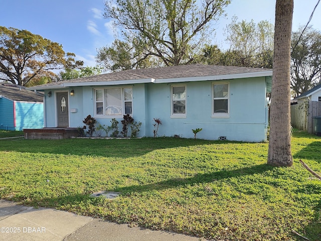 single story home with a front lawn, roof with shingles, and stucco siding