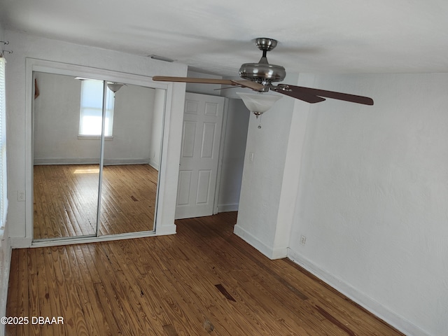 unfurnished bedroom with a ceiling fan, wood finished floors, visible vents, baseboards, and a closet