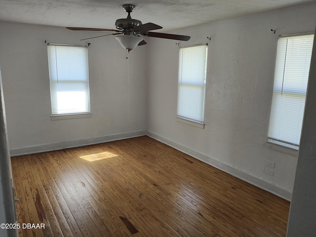 unfurnished room with hardwood / wood-style floors, baseboards, and ceiling fan