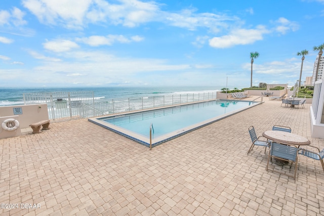 view of pool featuring a water view and a patio