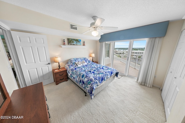 bedroom featuring a closet, a textured ceiling, access to exterior, light colored carpet, and ceiling fan