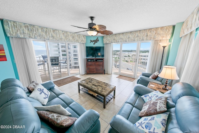 living room with a textured ceiling, a wealth of natural light, ceiling fan, and light tile patterned floors