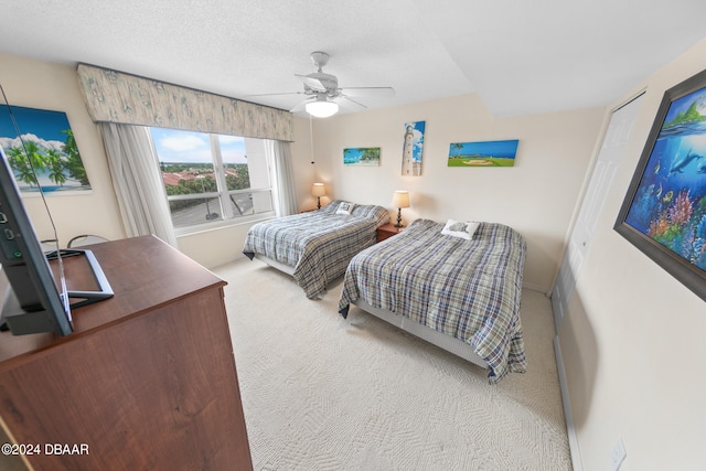 carpeted bedroom featuring ceiling fan and a textured ceiling