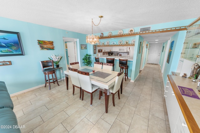 tiled dining room with a chandelier and a textured ceiling