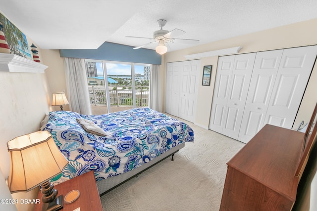 carpeted bedroom with multiple closets, a textured ceiling, ceiling fan, and access to exterior