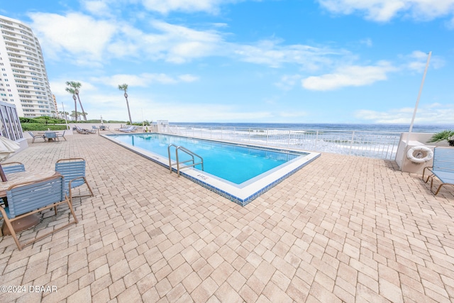 view of pool featuring a patio area and a water view