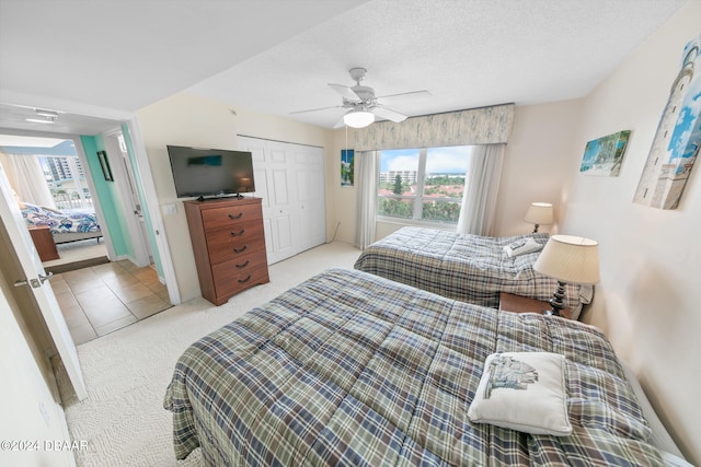 carpeted bedroom featuring a closet, multiple windows, a textured ceiling, and ceiling fan