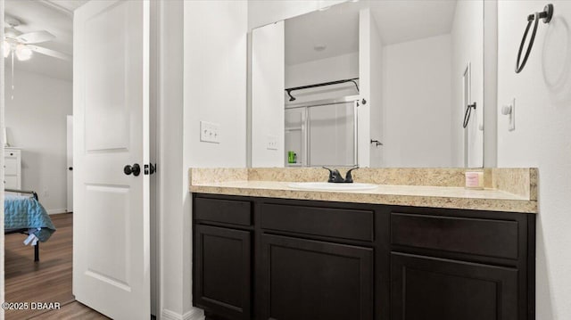 ensuite bathroom featuring vanity, ensuite bath, wood finished floors, and ceiling fan