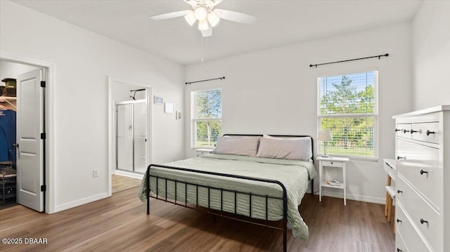 bedroom with a spacious closet, baseboards, ensuite bathroom, wood finished floors, and a ceiling fan