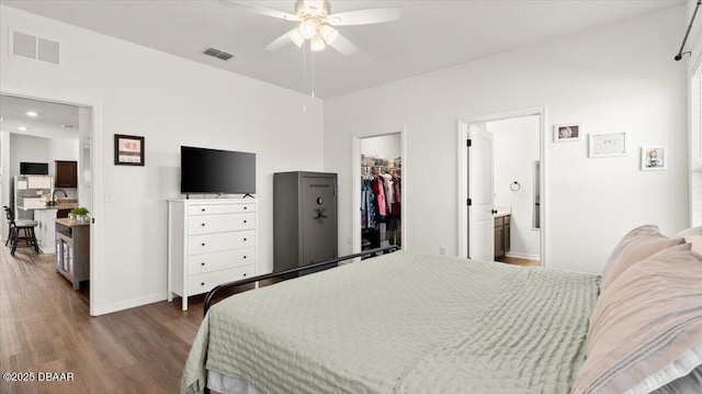 bedroom featuring a spacious closet, wood finished floors, visible vents, and ensuite bathroom