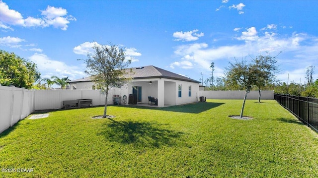 back of house featuring a lawn, stucco siding, a fenced backyard, a ceiling fan, and a patio