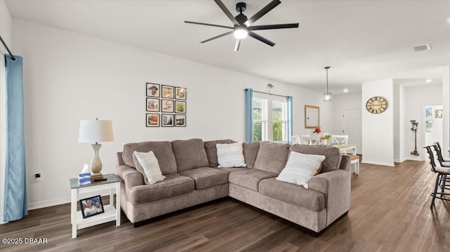 living area featuring dark wood finished floors, baseboards, visible vents, and ceiling fan