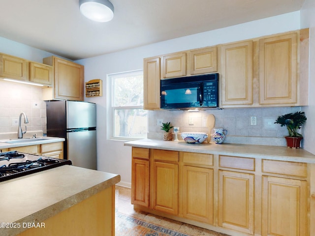823 E 10th Ave, New Smyrna Beach, FL 32169 - kitchen featuring black microwave, light brown cabinets, freestanding refrigerator, backsplash, and light countertops