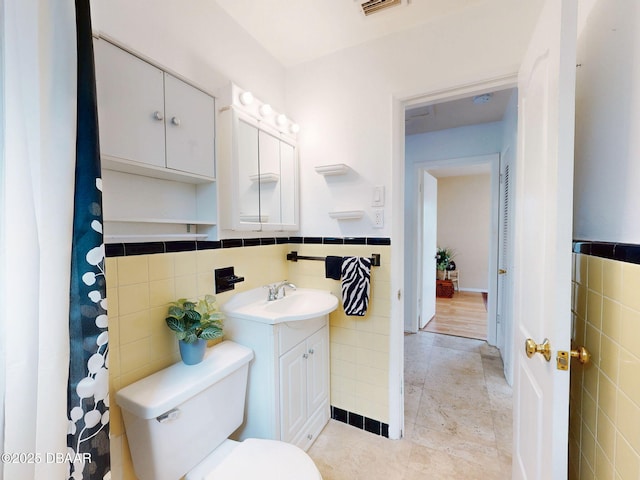 823 E 10th Ave, New Smyrna Beach, FL 32169 - full bath featuring tile walls, vanity, tile patterned floors, and wainscoting