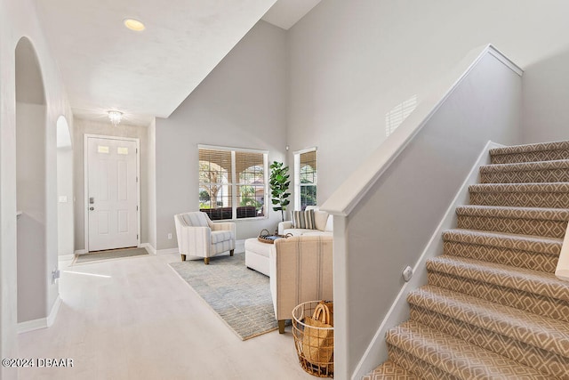 foyer with high vaulted ceiling and carpet