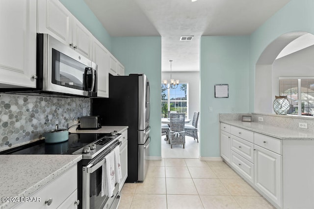 kitchen with stainless steel appliances, a chandelier, white cabinetry, and light stone counters