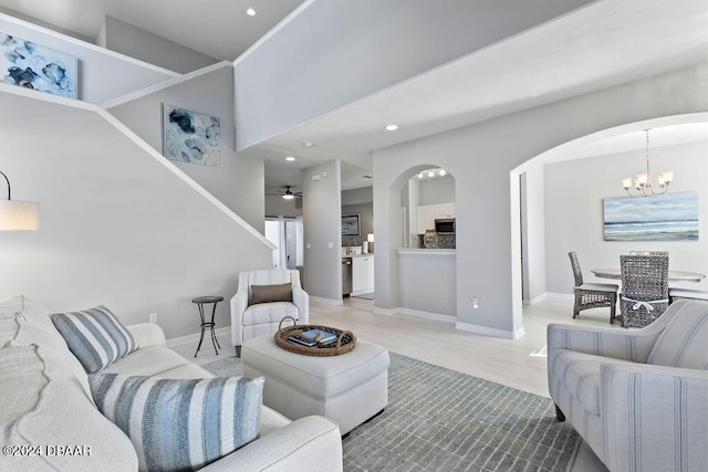 living room with a towering ceiling and ceiling fan with notable chandelier