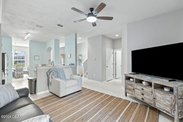 carpeted living room featuring ceiling fan with notable chandelier