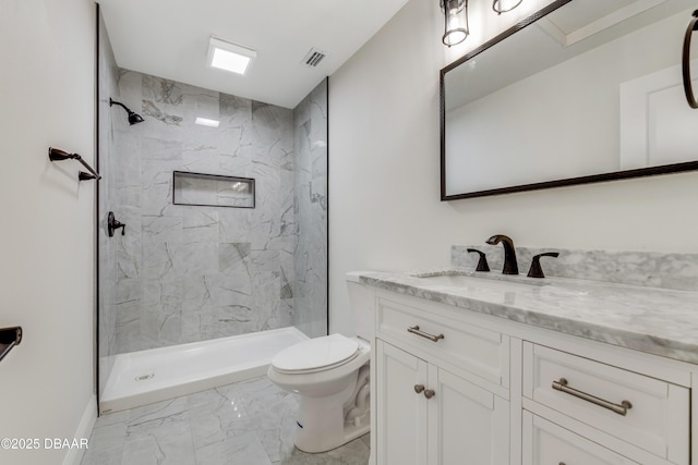 bathroom with toilet, a tile shower, and vanity