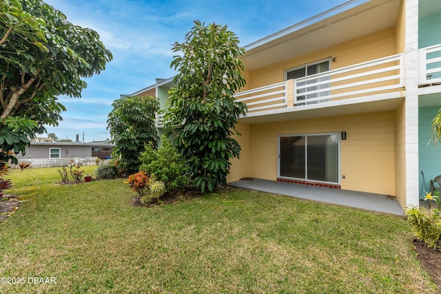 back of property with a balcony, a patio, and a yard