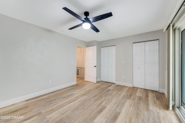 unfurnished bedroom with ceiling fan, light hardwood / wood-style floors, and multiple closets