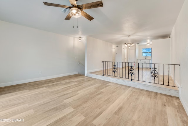 unfurnished room with ceiling fan with notable chandelier and light hardwood / wood-style floors