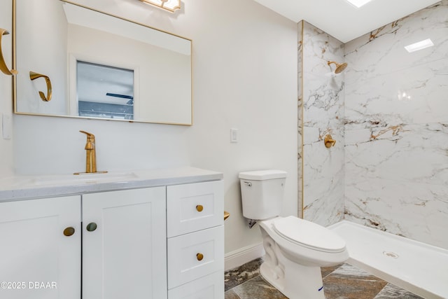 bathroom with toilet, tiled shower, and vanity