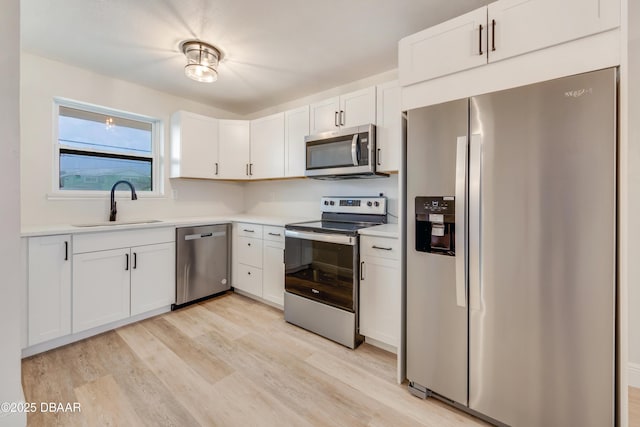 kitchen featuring appliances with stainless steel finishes, white cabinetry, and sink