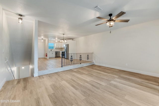 spare room with ceiling fan with notable chandelier, light wood-type flooring, and sink