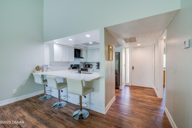 113 Club House Blvd, New Smyrna Beach, FL 32168 - kitchen with a kitchen bar, dark wood finished floors, a sink, wall chimney range hood, and white cabinets