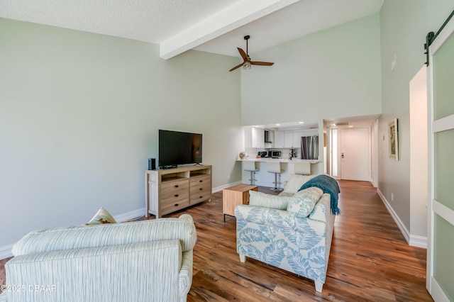 113 Club House Blvd, New Smyrna Beach, FL 32168 - living area featuring beam ceiling, a ceiling fan, a barn door, wood finished floors, and baseboards