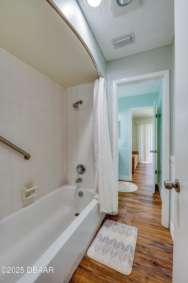 113 Club House Blvd, New Smyrna Beach, FL 32168 - bathroom featuring a textured ceiling, visible vents, baseboards, wood finished floors, and shower / bathtub combination with curtain