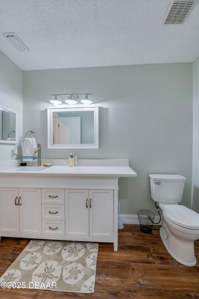 113 Club House Blvd, New Smyrna Beach, FL 32168 - bathroom with a textured ceiling, visible vents, toilet, wood finished floors, and vanity