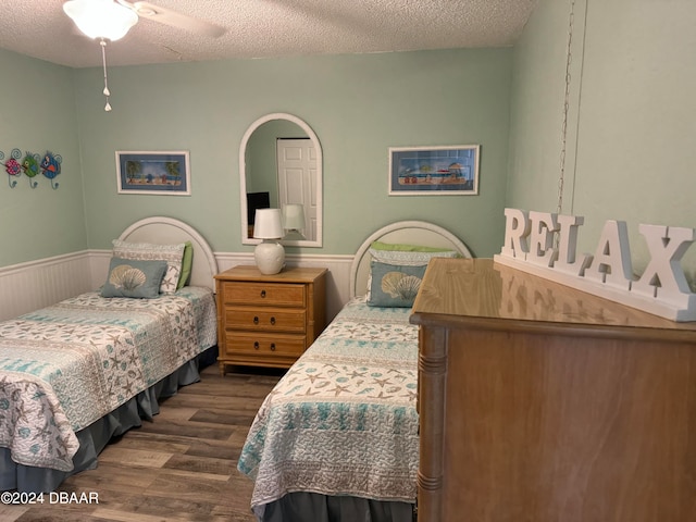 bedroom with ceiling fan, a textured ceiling, and dark hardwood / wood-style flooring