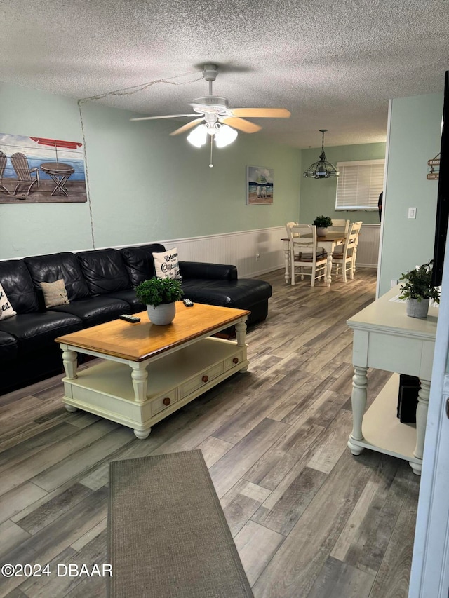 living room featuring hardwood / wood-style floors, a textured ceiling, and ceiling fan