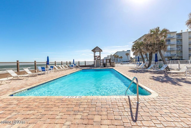 view of swimming pool featuring a patio area and a water view