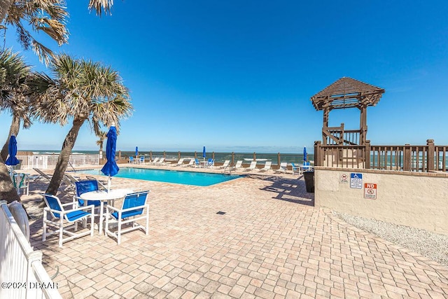 view of pool with a water view and a patio